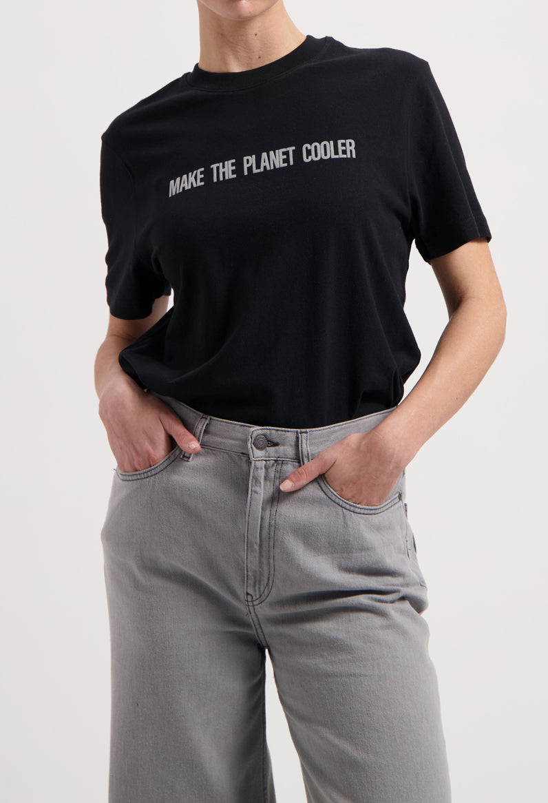 Sustainable MUD Jeans in classic black, made from organic cotton, paired with a white tee and casual white sneakers.