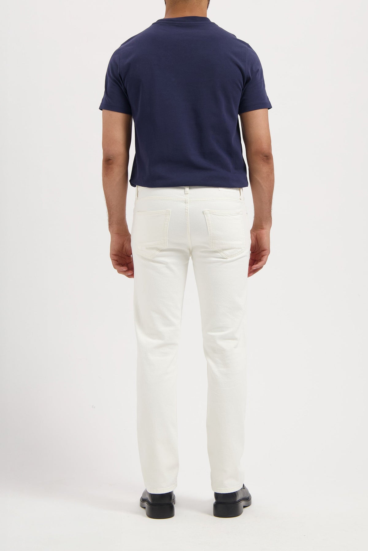 Sustainable MUD Jeans in dark indigo denim, paired with white sneakers, embodying ethical fashion.