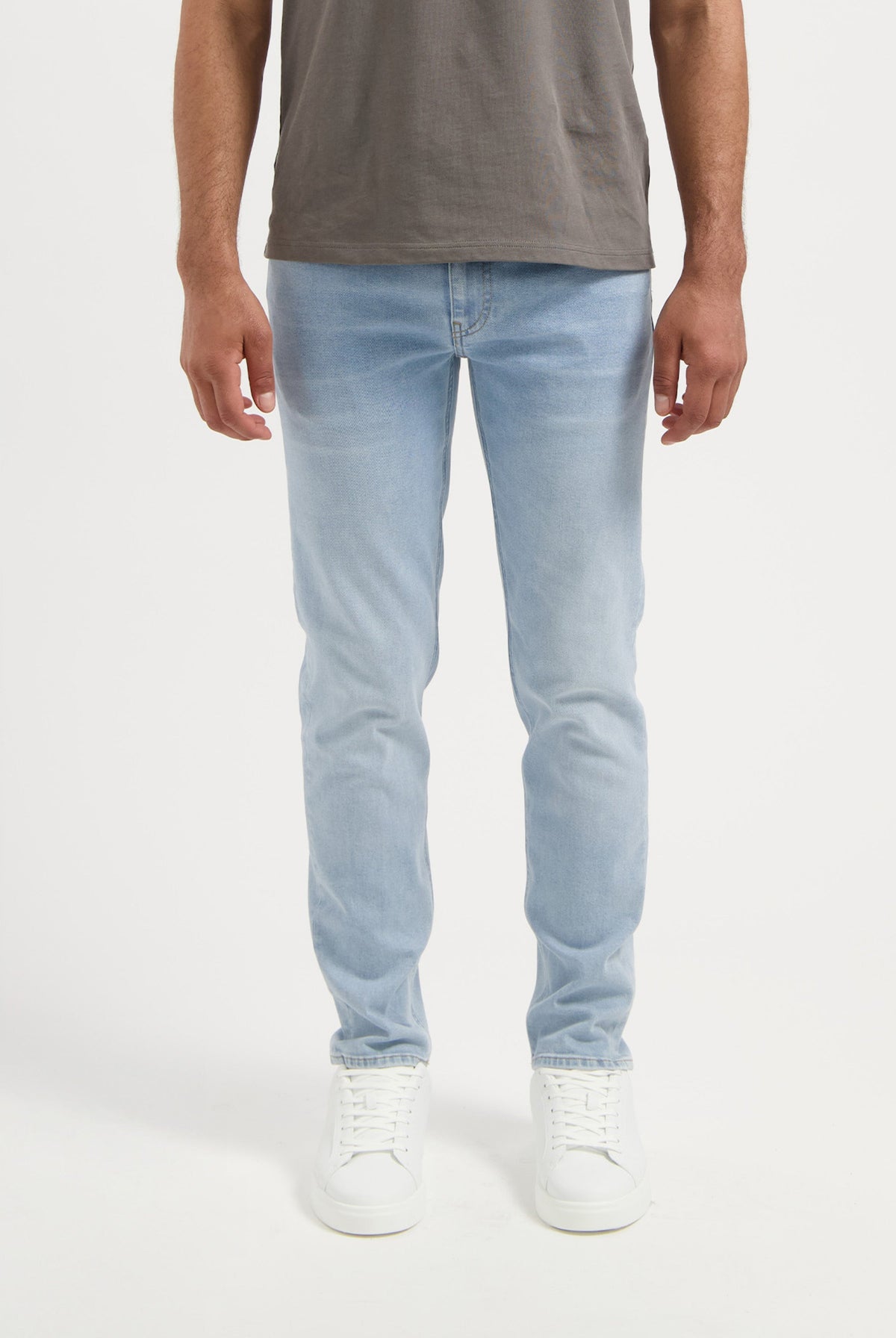 Sustainable MUD Jeans in beige, designed with ethical materials, paired with a gray t-shirt and white sneakers.