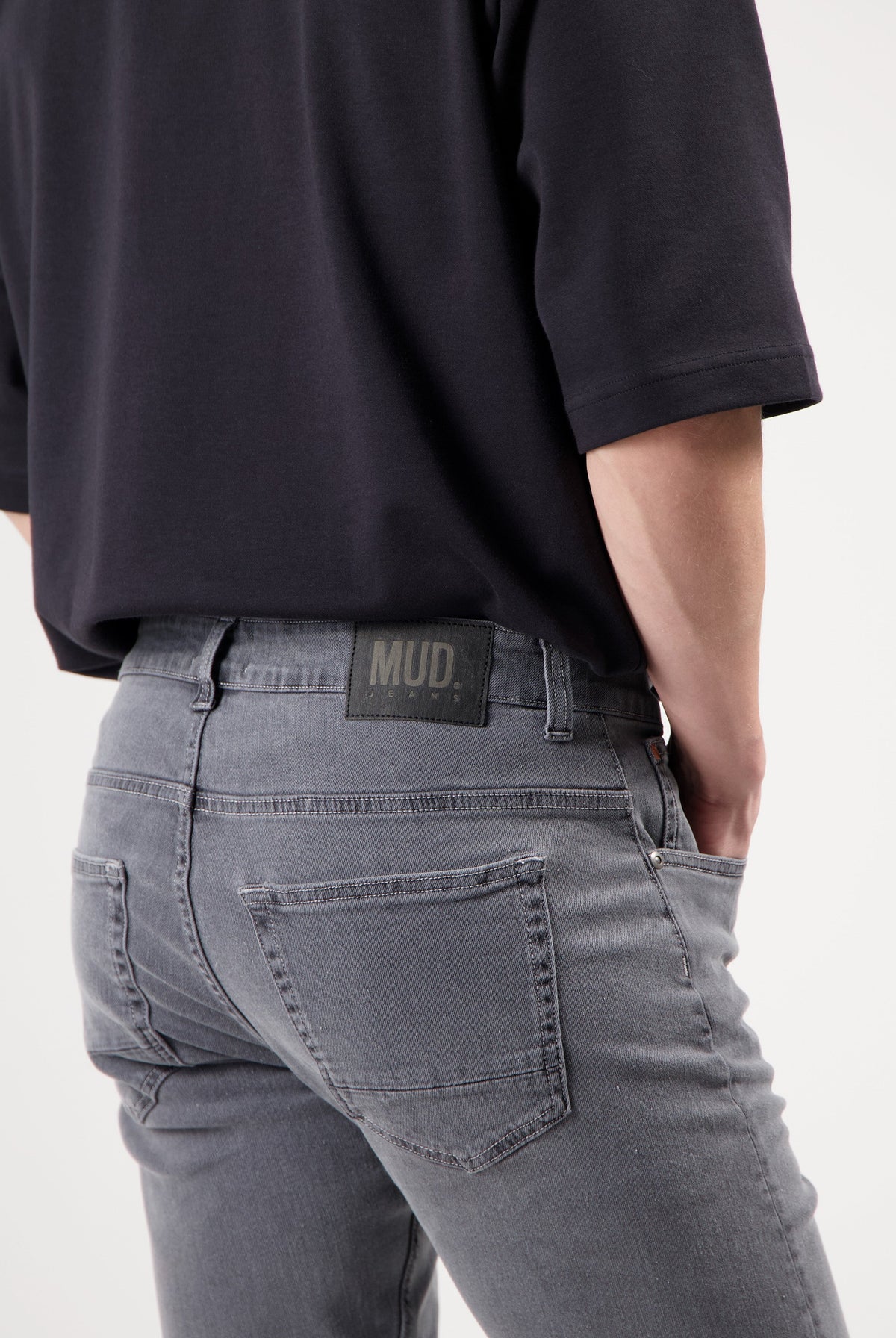 Sustainable Mud Jeans in dark gray, classic fit, made from ethical materials, paired with a white long-sleeve shirt.
