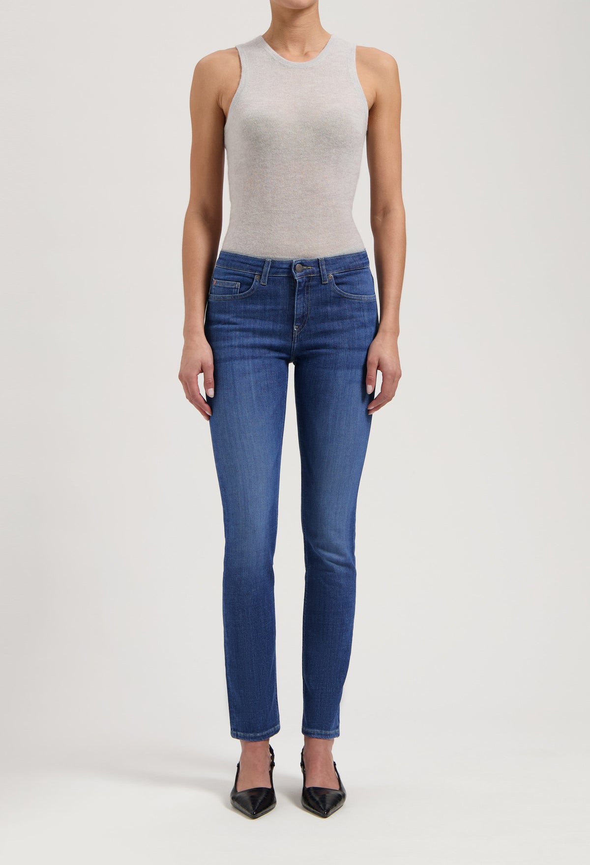 Slim-fit blue women’s jeans paired with a gray sleeveless top and black pointed-toe heels.