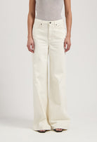 Woman wearing wide-leg, high-waisted cream jeans with a sleeveless gray top, showcasing elegant minimalist style.
