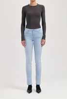 Slim-fit light blue denim jeans with a button closure, paired with a charcoal gray long-sleeve top, modeled standing.